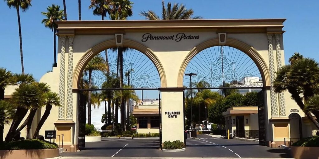 Un dirigente di Paramount discute con un avvocato durante una riunione, con un poster di Hollywood dietro di lui